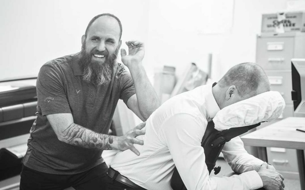 Un homme qui pratique un massage assis sur un client (en entreprise)
